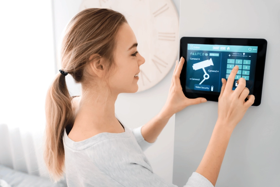 Woman using home security keypad to activate cameras and other devices